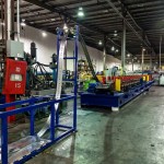 Roll forming feeder guiding strip into forming rollers.