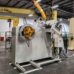 Uncoiler and leveler feeding flat metal strip.