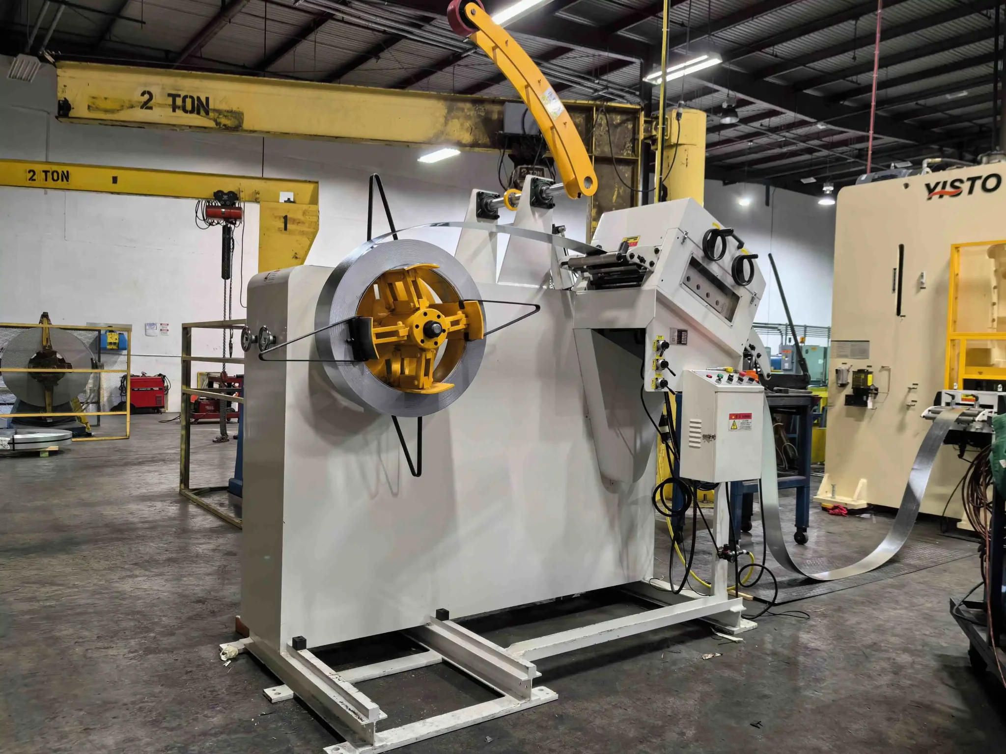 Uncoiler and leveler feeding flat metal strip.