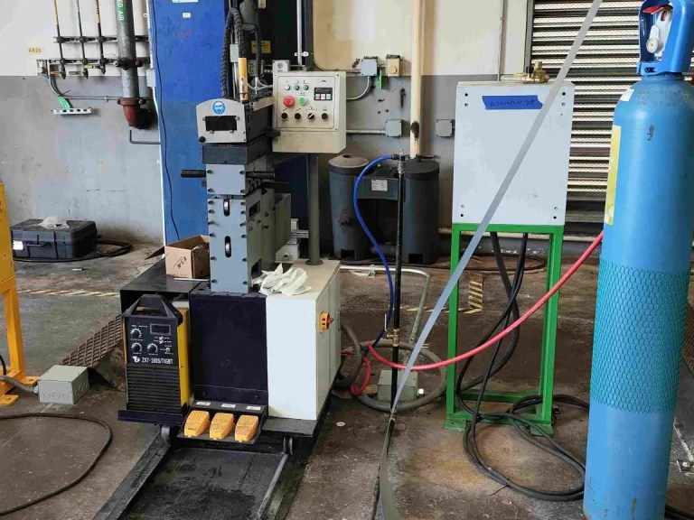 The coil end shearing and butt welder unit, showing a new coil being joined to the end of a depleted coil strip, with shearing blades and welding equipment visible, facilitating continuous operation.