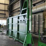 A tall vertical coil accumulator (loop pit or tower accumulator) designed to store a buffer of material, allowing the roll forming machine to run continuously while new coils are being joined or prepared.